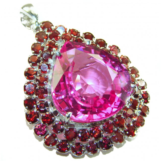 Penelope - 19.5 carat Pink Sapphire .925 Sterling Silver handmade Pendant Brooch - Close-up of pink sapphire pendant surrounded by red stones in silver setting.