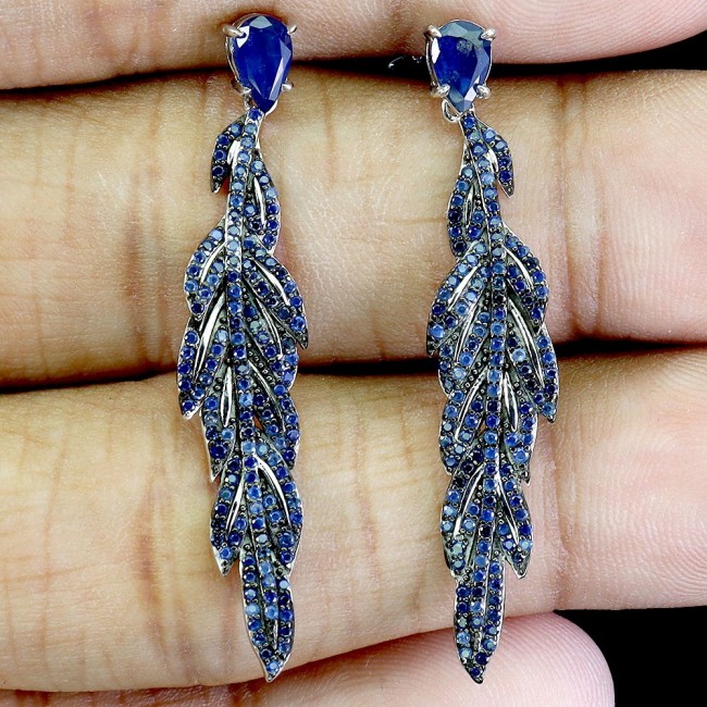 Giovanna - Authentic oval cut 9.9 carat Sapphire .925 Sterling Silver handcrafted earrings - Close-up of sapphire earrings with leaf design on hand.