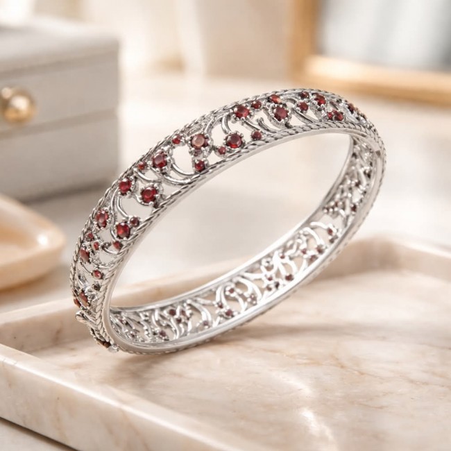 Authentic 18.2 carat Garnet .925 Sterling Silver handmade bangle Bracelet - Side view of garnet-studded sterling silver bangle on marble surface.