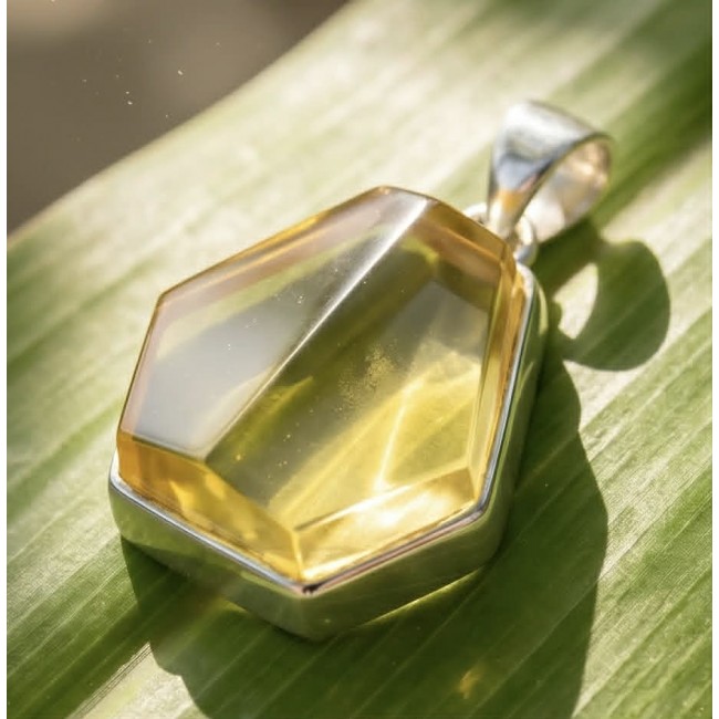 Prehistoric Authentic faceted Golden Baltic Amber .925 Sterling Silver beautifully handcrafted Pendant - Faceted Golden Baltic Amber pendant close-up on leaf background.