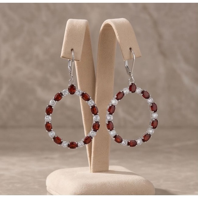 Red Royalty Authentic 24.9 carat Mozambique Garnet .925 Sterling Silver brilliantly handcrafted Statement earrings - Front view of red garnet and silver hoop earrings on a stand.