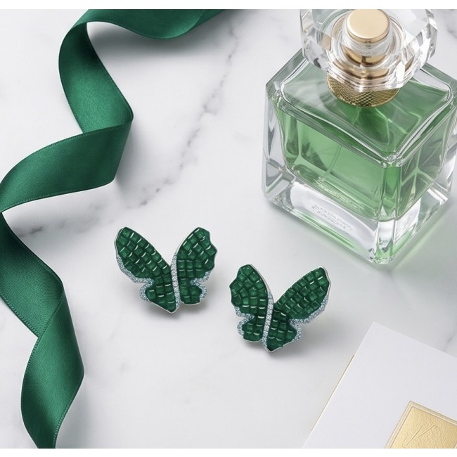 Incredible Butterflies genuine 15.5 CARAT Emerald .925 Sterling Silver handcrafted Earrings - Emerald butterfly earrings with perfume bottle and green ribbon on marble surface.