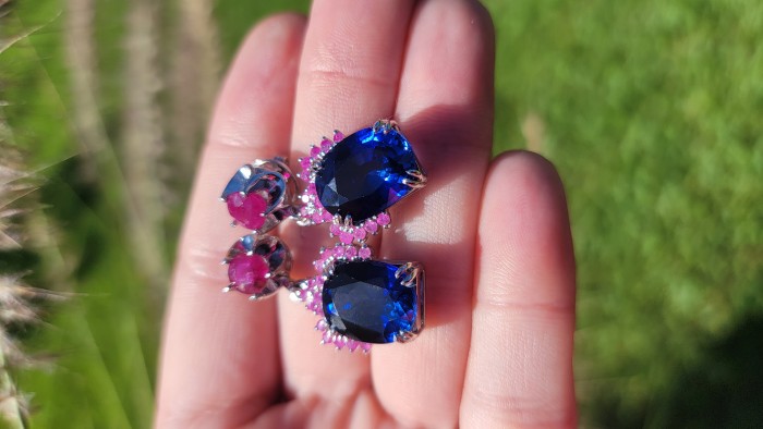 Deep Ocean 24.5 carat London Blue Topaz Ruby .925 Sterling Silver handmade earrings - Close-up of earrings with blue topaz and ruby stones in sunlight.
