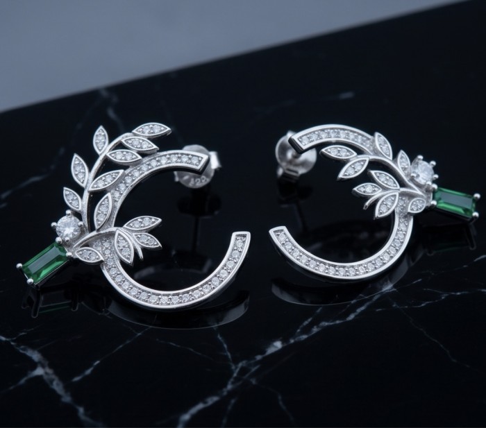 Floral design - 0.8 carat COLOMBIAN Emerald .925 Sterling Silver handmade Earrings - Floral earrings top view with emerald and leaf details on black surface.