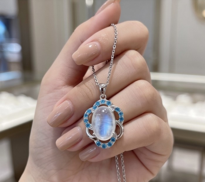 Genuine 7.2 carat Fire Moonstone .925 Sterling Silver handcrafted pendant - Close-up of moonstone pendant held in hand with turquoise accents.