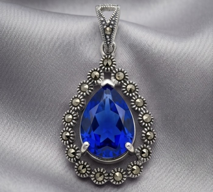 Julietta 14.5 carat London Blue Topaz Marcasite .925 Sterling Silver handmade Statement Pendant - Blue topaz pendant close-up with marcasite accents on satin background.