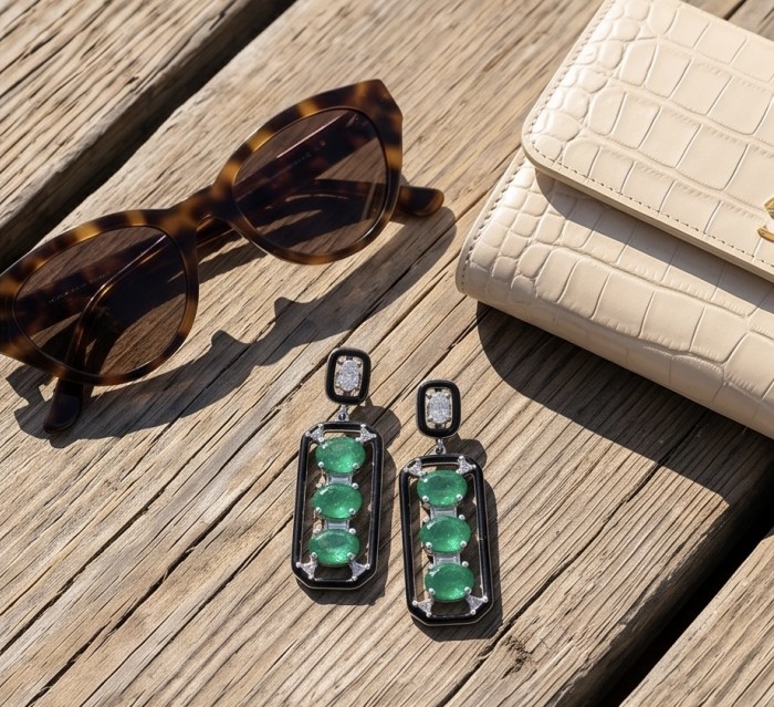 Art Deco 8.2 carat Colombian Emerald .925 Sterling Silver handcrafted Statement earrings - Emerald earrings with sunglasses and purse on wood background, top view.
