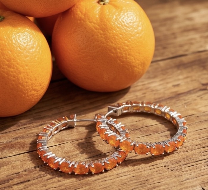 Valentina 3.7 carat Natural Fire Orange Opal rhodium over .925 Sterling Silver handcrafted inside - out Hoop earrings - Hoop earrings with orange opals on wood, oranges in background.