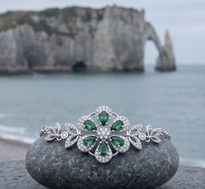 Giovanna - Authentic 7.9 carat Colombian Emerlad .925 Sterling Silver handcrafted Statement bracelet - Emerald bracelet on rock with coastal background, front view.