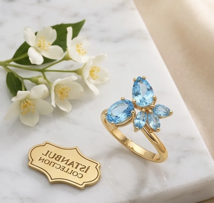 Pacifica 6.8 carat Swiss Blue Topaz 22K Gold over .925 Sterling Silver handcrafted ring size 8 - Top view of Pacifica Swiss Blue Topaz ring on marble with flowers.