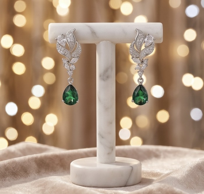 Valentina 2.2 carat Emerald .925 Sterling Silver dipped in rhodium Statement handcrafted earrings - Emerald earrings front view on marble display with bokeh background