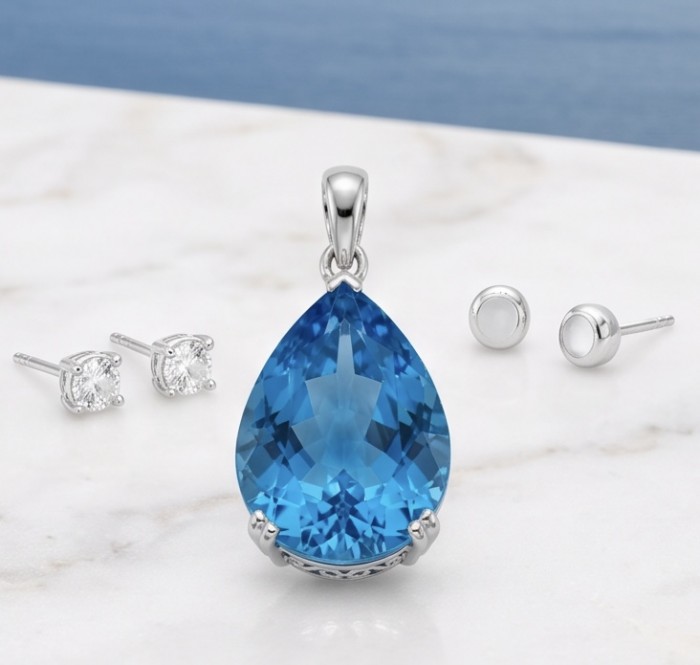 Tiffany Incredible pear cut 22.4 carat Swiss Blue Topaz rhodium over .925 Sterling Silver handcrafted pendant - Blue topaz pendant and earrings on marble surface, front view.