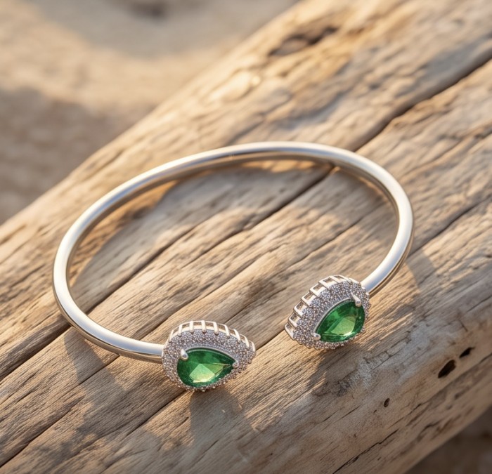 Victoria 8.7 ctw Colombian Emerald rhodium over .925 Sterling Silver handcrafted Statement bracelet - Victoria Emerald Bracelet on wood, showcasing dual green stones.