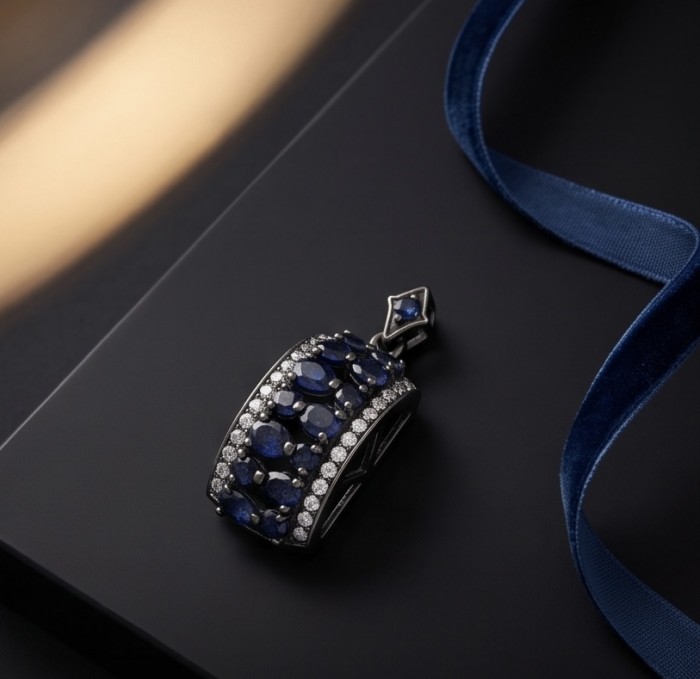 Vintage Beauty 9.7 carat Mozambique Sapphire Black Rhodium over .925 Sterling Silver handcrafted pendant - Sapphire pendant side view on dark surface with blue ribbon.