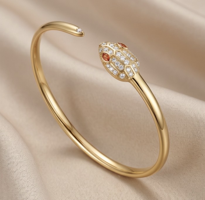 Precious Boa Snake Genuine 0.7 carat orange Sapphire .925 Sterling Silver dipped in 14K Gold handcrafted Bracelet - Gold snake bracelet with sapphire head on fabric background, side view.