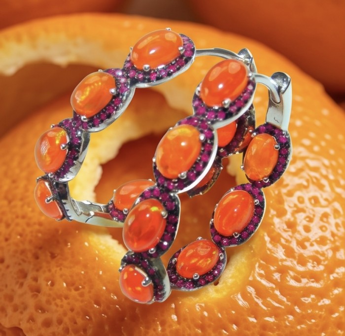 Valentina 8.7 carat Natural Fire Orange Opal rhodium over .925 Sterling Silver handcrafted inside - out Hoop earrings - Close-up of Valentina 8.7ct Fire Orange Opal bracelet on orange background