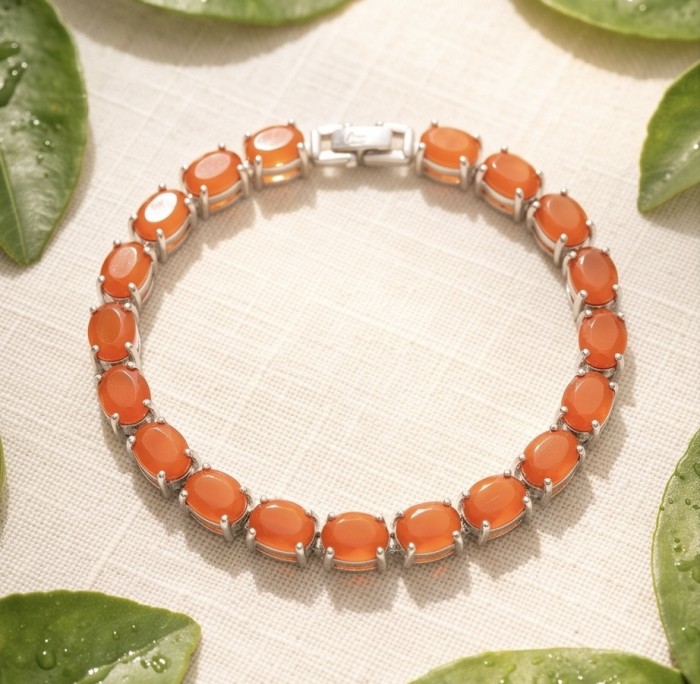 Sublime Brilliance 26.8 carat Authentic Orange Fire Opal .925 Sterling Silver handcrafted bracelet - Orange gemstone bracelet, top view on fabric with leaves.