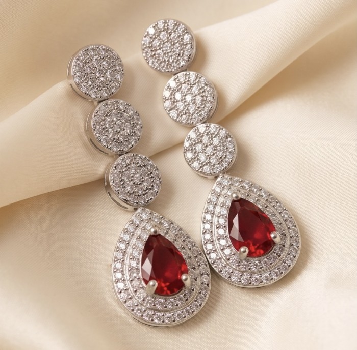 Exquisite 3.4 ctw Mozambique Ruby .925 Sterling Silver handcrafted Statement earrings - Elegant ruby and silver earrings on fabric background, top view.