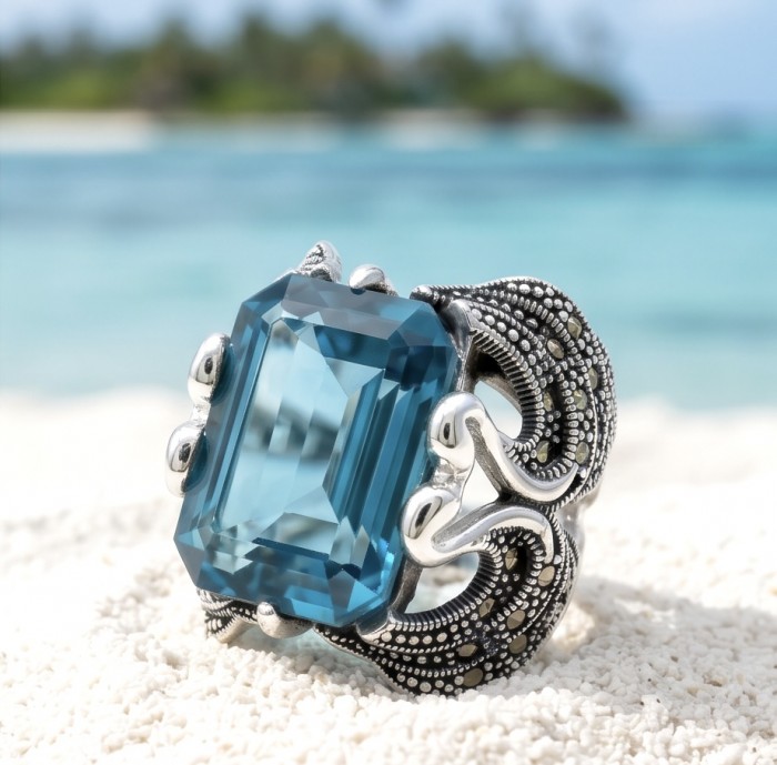 Two Swans Authentic 27.4 carat Aquamarine .925 Sterling Silver brilliantly handcrafted large Statement Ring size 8 - Close-up of 27.4 carat aquamarine ring with swan design on beach background