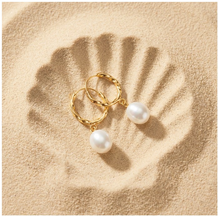 Genuine Pearl 14K Gold over .925 Sterling Silver handcrafted Statement Earrings - Pearl and gold hoop earrings on sand with shell imprint, top view.