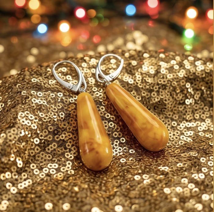 Very Special product - Wonderful natural Buttescotch Baltic Amber .925 Sterling Silver entirely handcrafted earrings - Amber earrings on gold sequined fabric, festive lights in background.