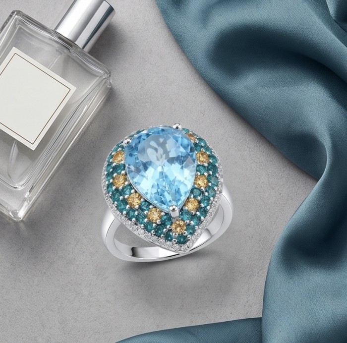 Venus 11.8 carat Swiss Blue Topaz .925 Sterling Silver dipped in rhodium handcrafted ring size 7 - Top view of Venus Swiss Blue Topaz ring with perfume and silk fabric.