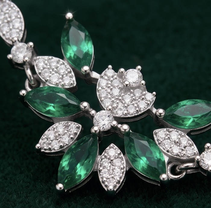Giovanna - Authentic 6.2 carat Colombian Emerlad .925 Sterling Silver handcrafted Statement bracelet - Close-up of emerald and diamond jewelry with leaf pattern.