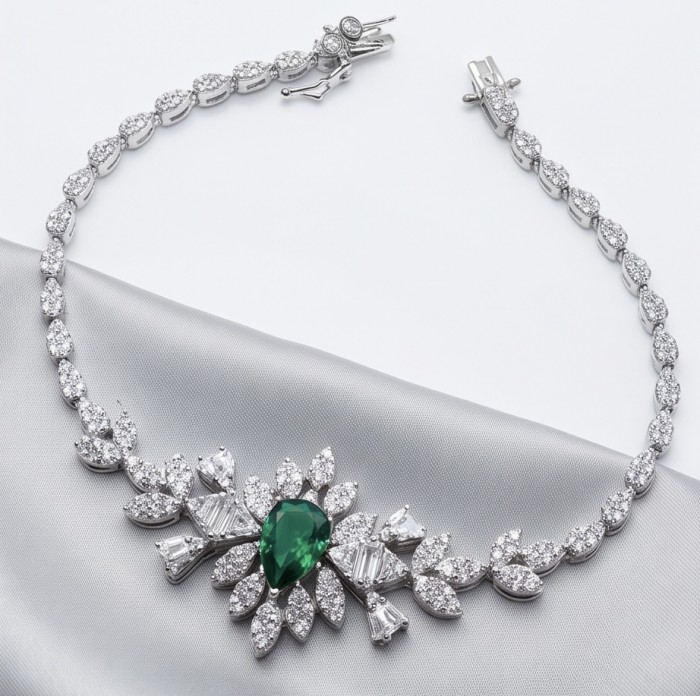 Giovanna - Authentic 4.5 carat Colombian Emerlad .925 Sterling Silver handcrafted Statement bracelet - Necklace with emerald and diamonds on gray fabric, front view.