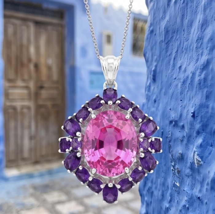 Tiffany Incredible oval cut 20.4 carat Pink Sapphire Amethyst .925 Sterling Silver handcrafted pendant - Close-up of pendant with pink sapphire and purple stones against blue wall.