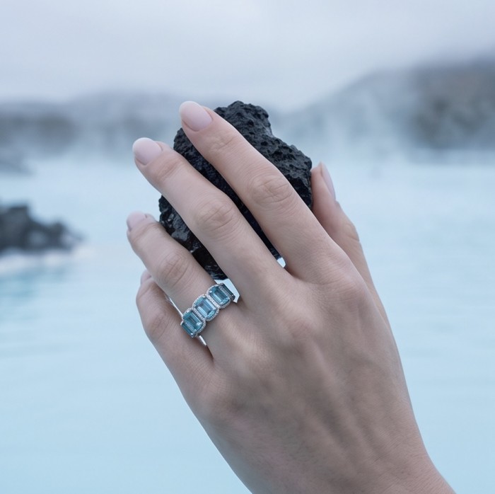 Angel's Wish 22.8 carat Aquamarine .925 Sterling Silver handcrafted infinity ring size 6 - Aquamarine ring worn on hand, holding dark rock, blue water background.
