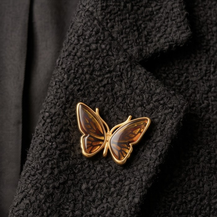 Golden Butterfly natural carved Baltic Amber .925 Sterling Silver dipped in 22K Real Gold handmade Pendant - Golden butterfly amber pin on black textured fabric, front view.