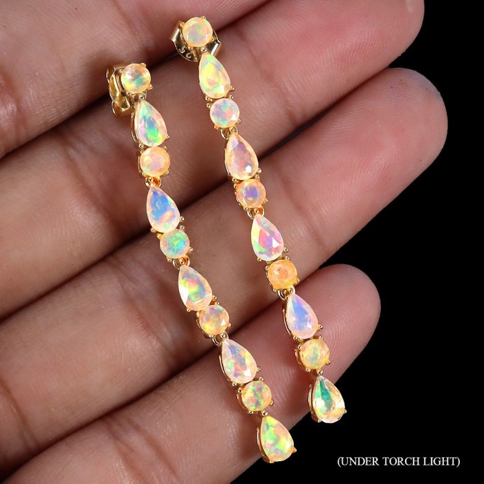 Valentina 2.9 carat Natural Australian Opal .925 Sterling Silver dipped in 22K Gold handcrafted earrings - Opal earrings shown in hand under torch light, highlighting iridescence.