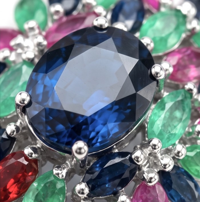 Enchanted Ocean oval cut 18.5 carat London Blue Topaz .925 Sterling Silver handmade Pendant - Close-up of Enchanted Ocean Blue Topaz surrounded by colorful gemstones.