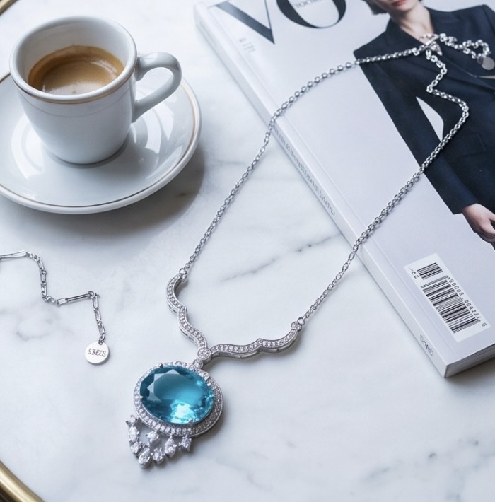 A Wild Ocean genuine 27.4 carat Paraiba Tourmaline .925 Sterling Silver handmade Statement necklace - Paraiba Tourmaline necklace on magazine, angled tabletop view