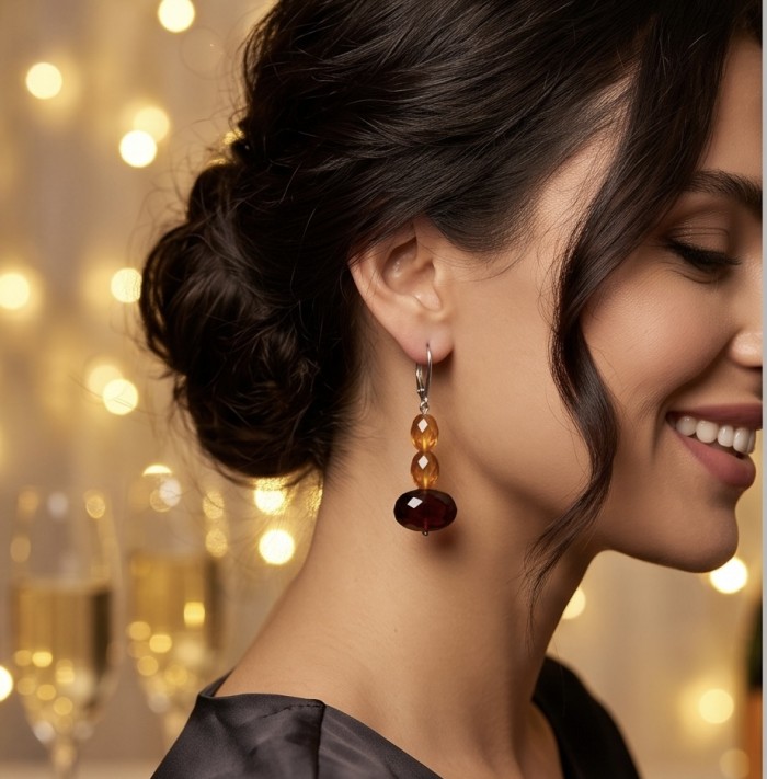 Luminous fossilized Beauty natural Baltic Amber .925 Sterling Silver entirely handcrafted earrings - Side view of woman wearing amber earrings, festive lights in background.