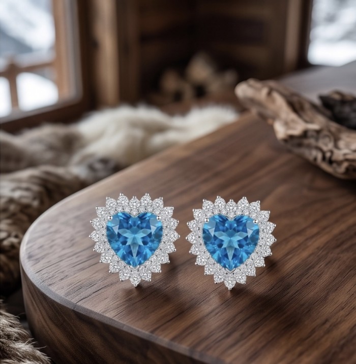 Heartes 6.7 carat Swiss Blue Topaz .925 Sterling Silver Handcrafted earrings - Close-up of heart-shaped Swiss Blue Topaz earrings on a wooden surface.