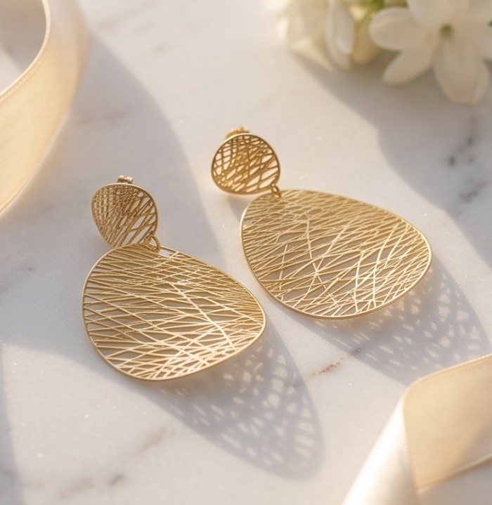 Dubai Style - .925 Sterling Silver dipped in 22K Gold handmade Earrings - Close-up of gold teardrop earrings with crisscross pattern on marble.