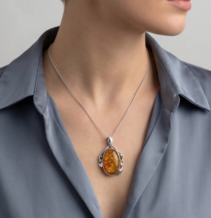 Sea Treasure Prehistoric Authentic Golden Baltic Amber .925 Sterling Silver beautifully handcrafted Pendant - Necklace with Baltic amber pendant worn on neck, light blue shirt background.
