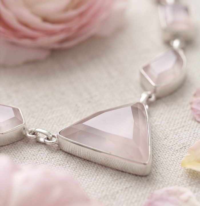 Moonlight Serenade authentic 32.5 carat Brazilian Rose Quartz rhodium over .925 Sterling Silver handcrafted necklace - Close-up of a Brazilian Rose Quartz necklace with pink rose petals.