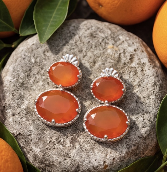 Valentina 4.9 carat Natural Orange Opal rhodium over .925 Sterling Silver handcrafted earrings - Orange Opal earrings on stone with citrus background, top view.