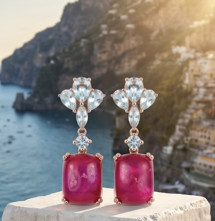 Maria Rosa - Magnificent Jewel 12.5 carat Mozambique Ruby .925 Sterling Silver dipped in 22K Rose Gold handcrafted earrings - Elegant earrings with rubies and blue stones, front view, scenic backdrop.