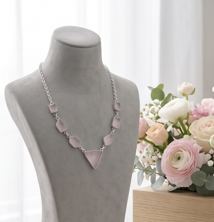 Moonlight Serenade authentic 32.5 carat Brazilian Rose Quartz rhodium over .925 Sterling Silver handcrafted necklace - Necklace on display near flowers, frontal view