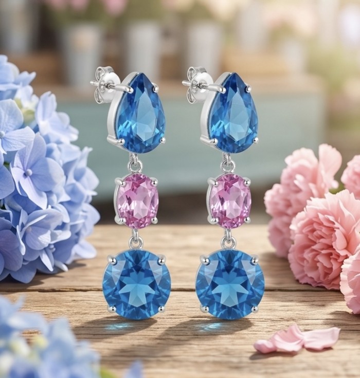 Exquisite 24.7 carat Swiss Blue Topaz rhodium over .925 Sterling Silver Handcrafted Statement earrings - Blue and pink gemstone earrings on wooden surface with flowers.