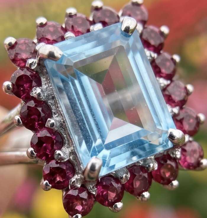 Atlantica 5.8 carat Swiss Blue Topaz .925 Sterling Silver dipped in rhodium handcrafted ring size 9 - Close-up of Swiss Blue Topaz ring with red gems in sterling silver setting.