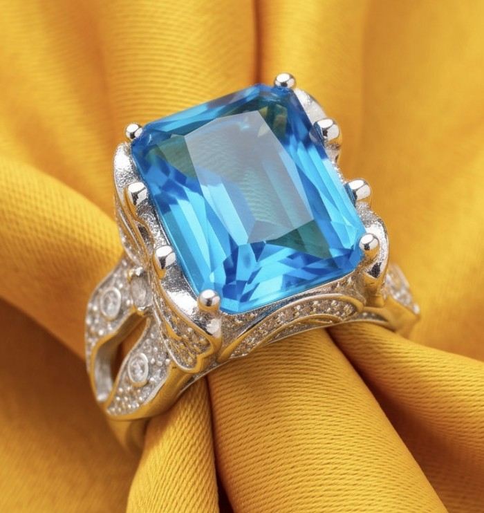 Blue OCEAN 14.3 carat Swiss Blue Topaz .925 Sterling Silver dipped in rhodium handcrafted ring size 7 1/4 - Blue Swiss Topaz ring in sterling silver on yellow fabric, stone close-up.