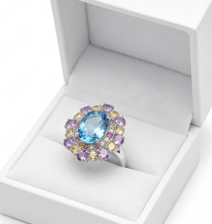 Pacifica - Authentic 33.8 carat Swiss Blue Topaz Rhodium over .925 Sterling Silver handcrafted Large Statement ring size 7 - Oval blue topaz ring in open box, top view, surrounded by purple/yellow gems.