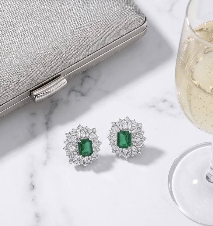 Giovanna - Authentic 7.9 carat COLOMBIAN EMERALD .925 Sterling Silver dipped in rhodium handcrafted earrings - Emerald earrings with diamonds, top view, near silver clutch and champagne.