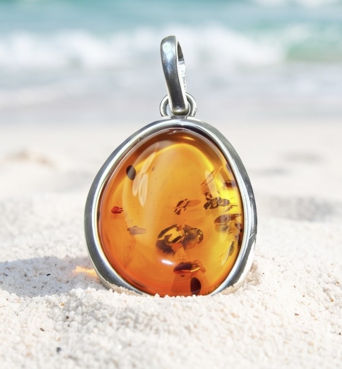 Prehistoric Authentic Golden Baltic Amber .925 Sterling Silver beautifully handcrafted Pendant - Amber pendant close-up on sand, beach in background
