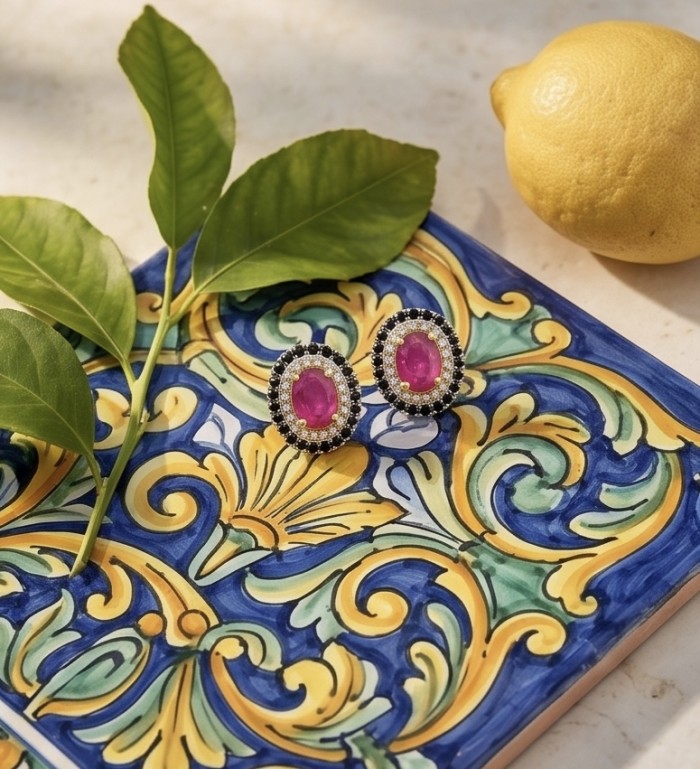 Born to Glam uthentic 3.2 carat Ruby 2 tones .925 Sterling Silver handcrafted earrings - Ruby earrings on colorful tile with lemon and leaves, top view.