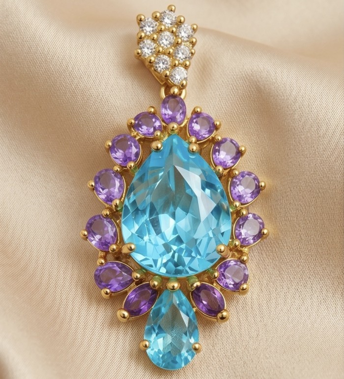 Oceania pear cut 15.8 carat Swiss Blue Topaz .925 Sterling Silver dipped in 22K Gold Handcrafted Pendant - Close-up of Oceania pendant with blue topaz and purple stones on fabric.